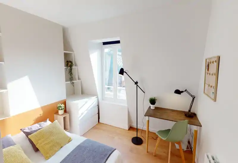 Bright, neatly styled bedroom with a comfortable double bed, warm textiles and a small desk by the window — ideal for restful stays or remote work.