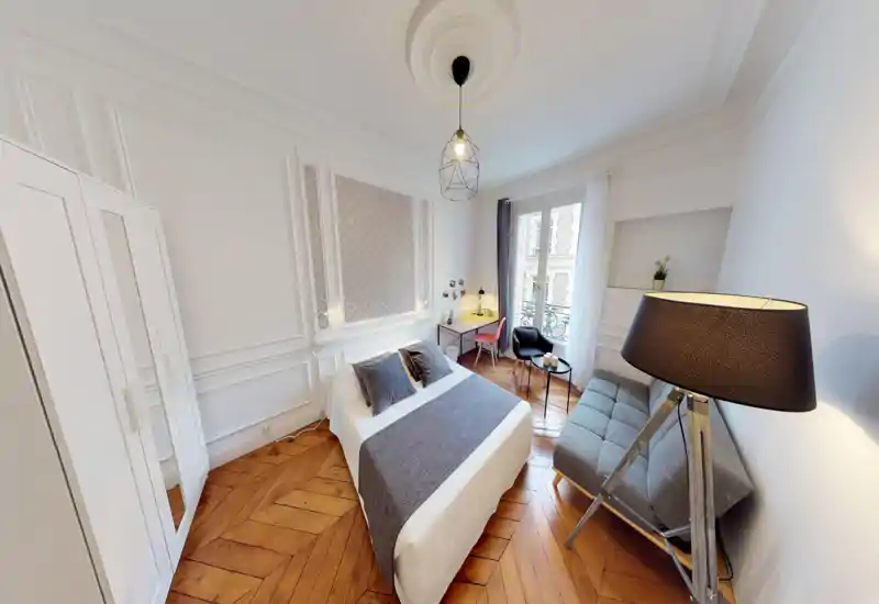 Bright, stylish bedroom with a centrally placed double bed, decorative cushions and a soft throw. Wooden herringbone floor, desk by the window and cozy seating make this room ideal for rest and light work.