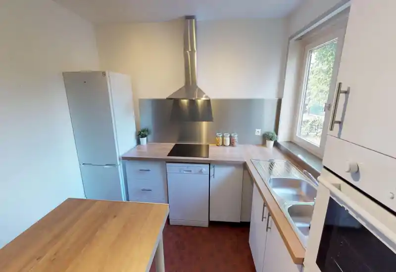 Bright attic-style kitchen with visible countertops and cabinets; image is heavily corrupted but shows workable layout and natural light.