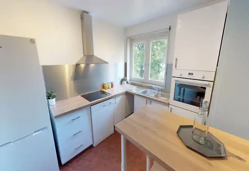 Bright kitchen space with visible countertops and cabinetry; image is heavily distorted but suggests a compact, well-lit cooking area with windows.