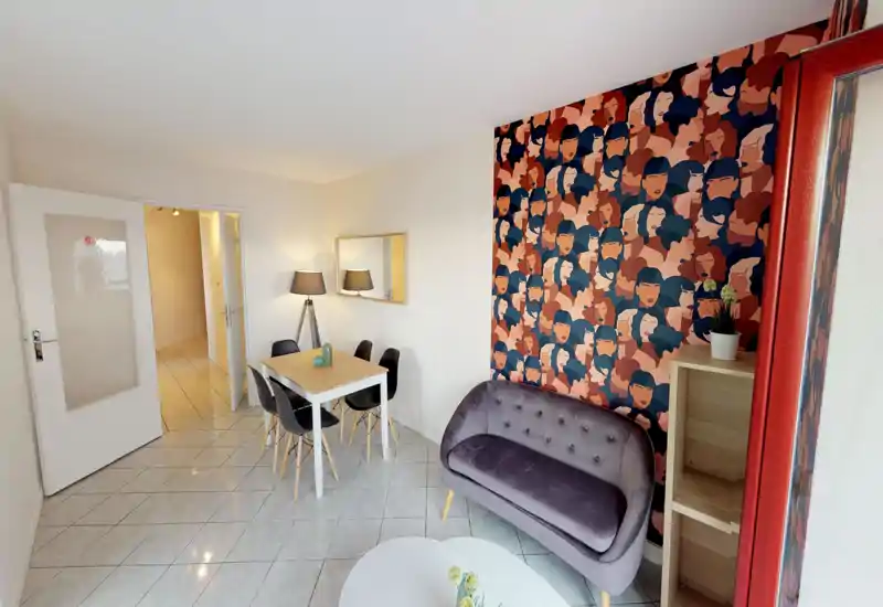 Bright, stylish living area with a small sofa, dining table for four and decorative feature wallpaper creating a modern, cozy atmosphere.
