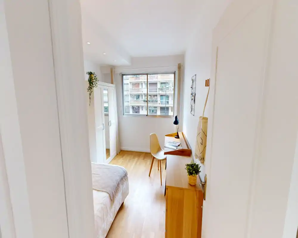 Bright, neatly staged bedroom with a visible double bed, wardrobe and a wooden desk by the window. Natural light and warm wooden flooring create a welcoming atmosphere ideal for rental photos.
