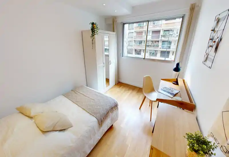 Bright, modern bedroom with a comfortable double bed, wooden flooring and a desk by the window. Large window provides abundant natural light and a wardrobe with mirror adds storage and functionality.