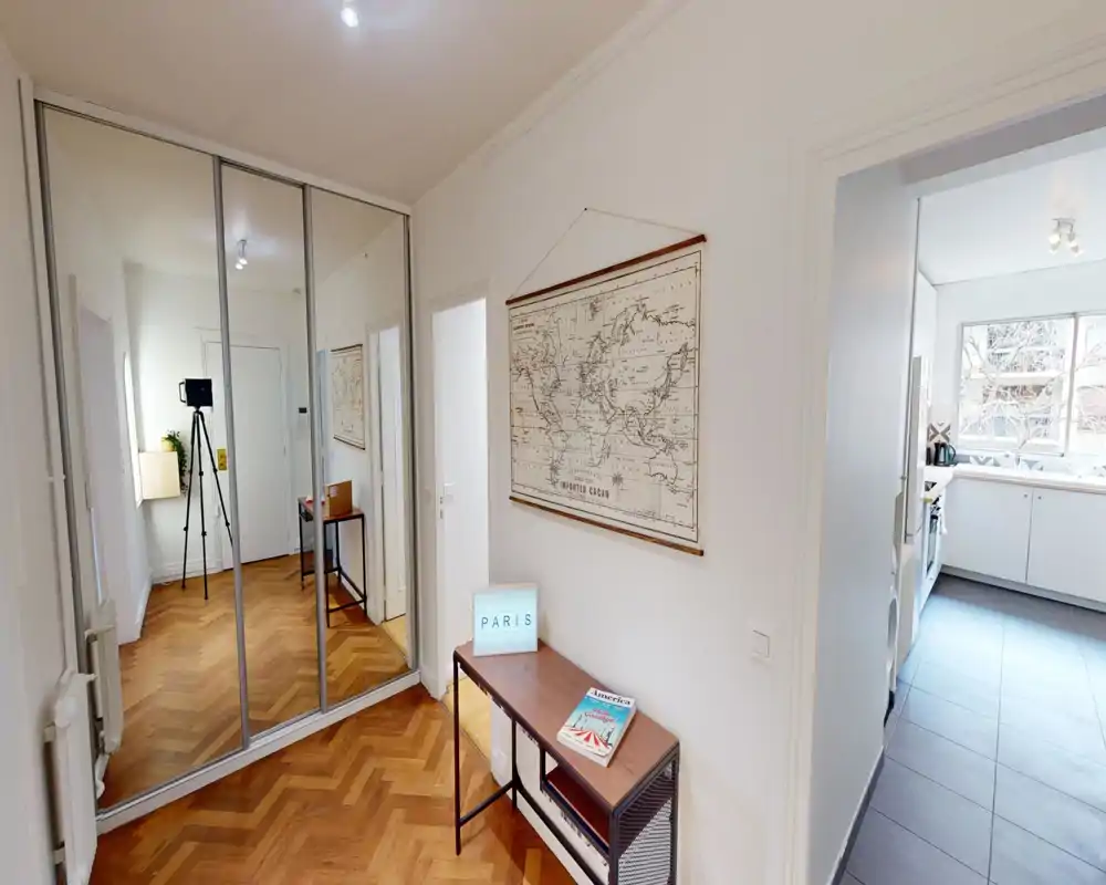 Bright, welcoming entrance hall with herringbone parquet, wall mirror/wardrobe doors, a slim console table and decorative map — leads directly to the kitchen.