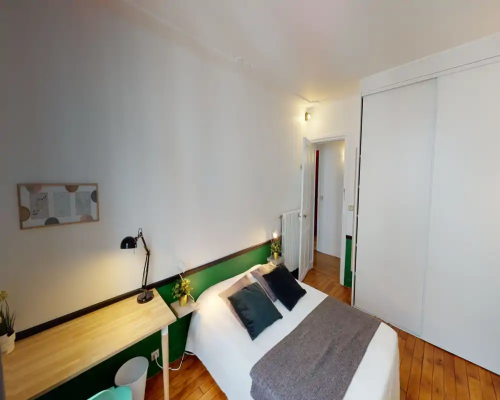 Bright, cozy bedroom with a double bed, soft textiles and bedside lamps; built-in sliding wardrobe and wooden floors add warmth.