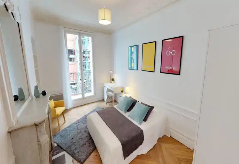 Bright, stylish bedroom with a centrally placed double bed, soft textiles, a desk by the window and tasteful wall art — ideal for a cozy city stay.