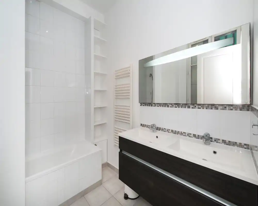 Bagno moderno e luminoso con vasca incassata, mobile lavabo doppio, grande specchio e piastrelle a parete — design pulito e minimal perfetto per annunci.