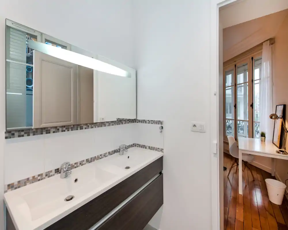 Bagno moderno con doppio lavabo, grande specchio e decorazione in mosaico. Design luminoso e pulito con sanitari contemporanei.