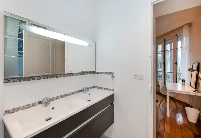 Bagno moderno con doppio lavabo, grande specchio e decorazione in mosaico. Design luminoso e pulito con sanitari contemporanei.