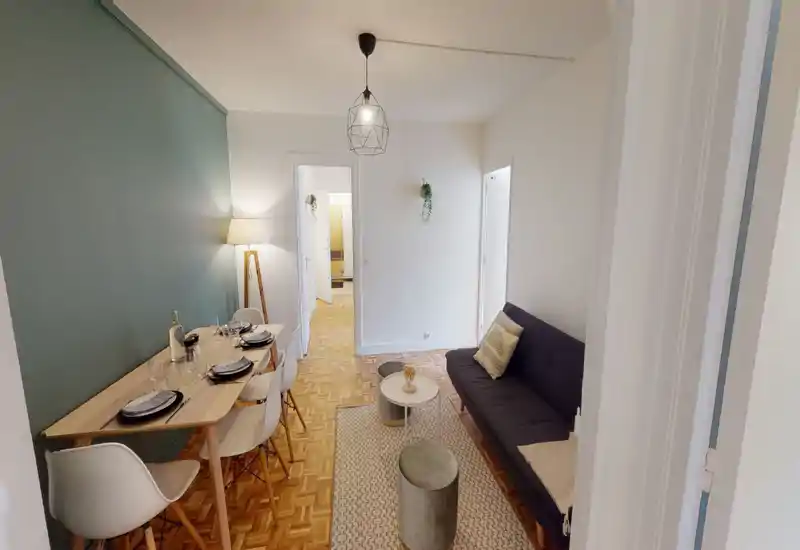 Bright, well-styled living area with a compact sofa, coffee tables and a dining table for four; modern lighting and soft textiles create a cozy, functional space ideal for short-term rentals.