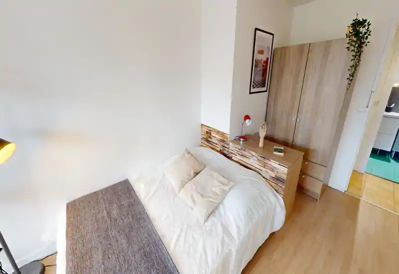 Bright, well-styled bedroom with a double bed, soft pillows and coordinated wooden furniture. Ideal for rental photos thanks to clean linens and warm decorative touches.