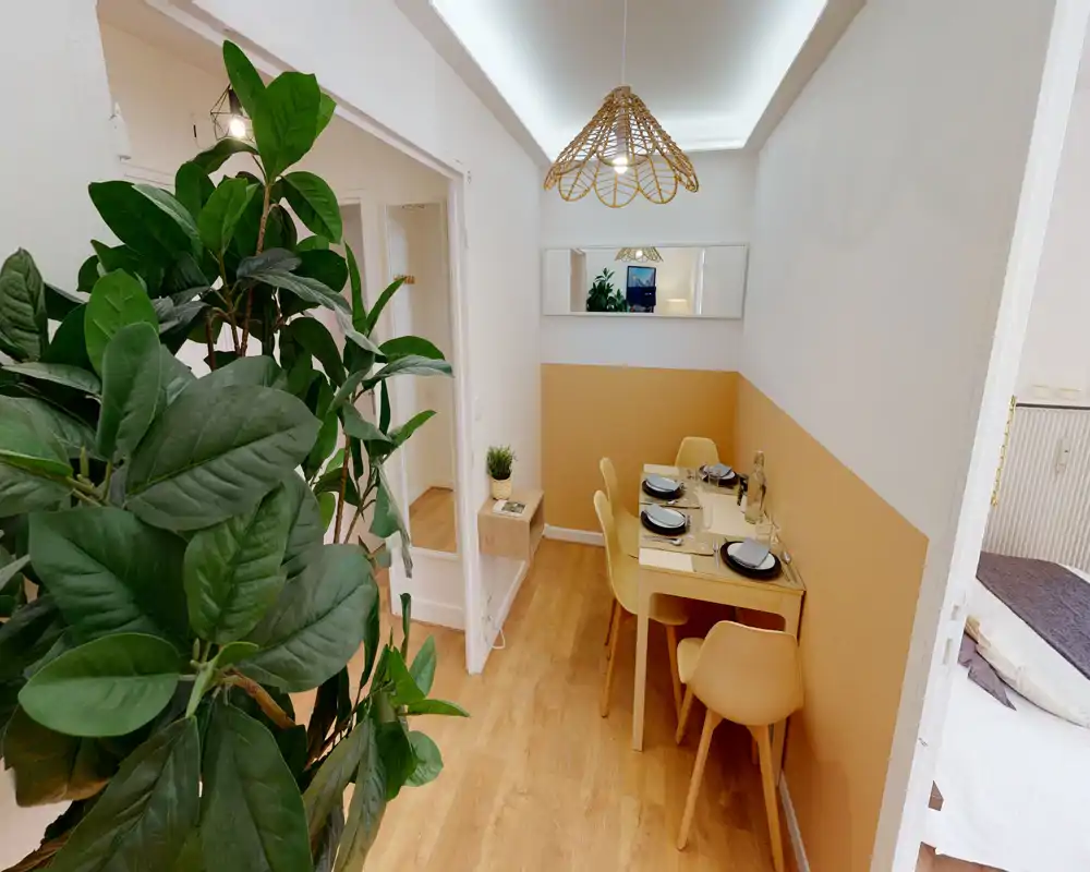 Coin repas compact et stylé avec table dressée pour quatre, mur bicolore chaleureux, suspension en rotin et chaises modernes assorties — idéal pour des repas cosy.