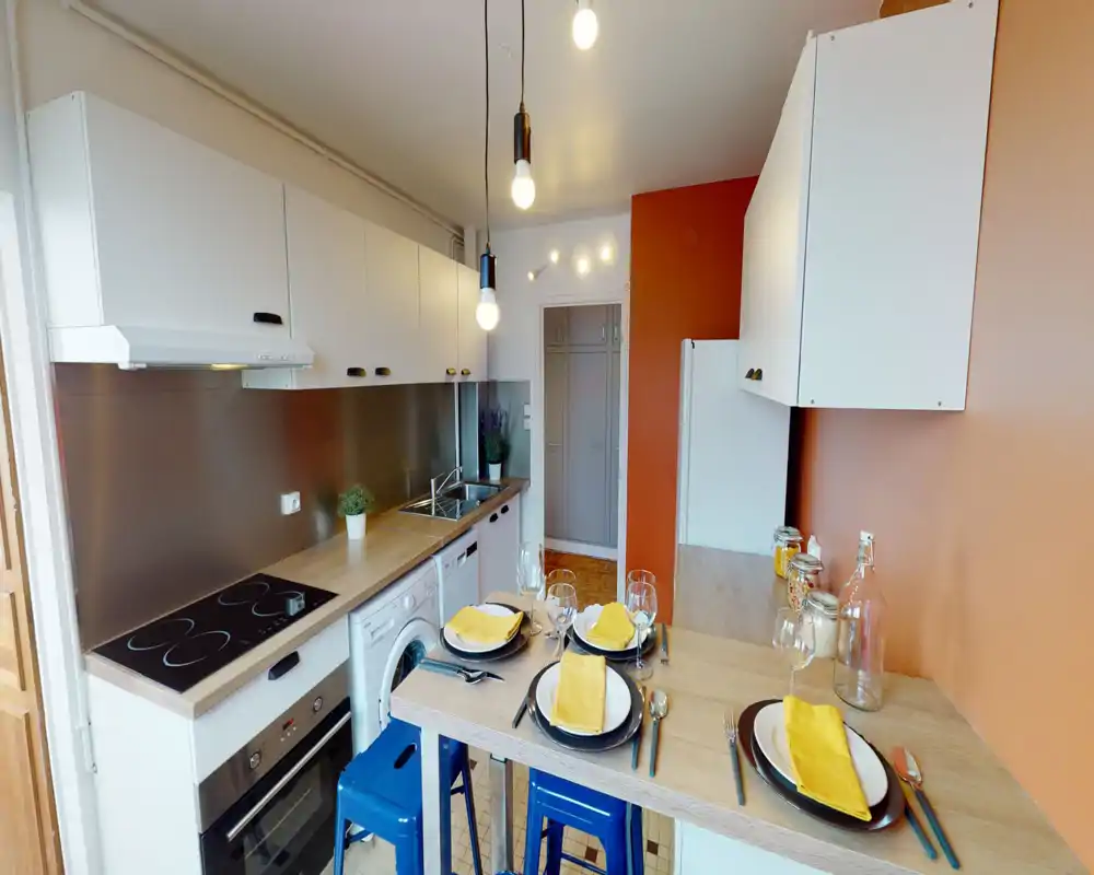 Bright modern kitchen with integrated oven and stovetop, wooden countertops and an island-style breakfast bar set for four. White cabinets and warm orange accent wall create a cozy, stylish feel.
