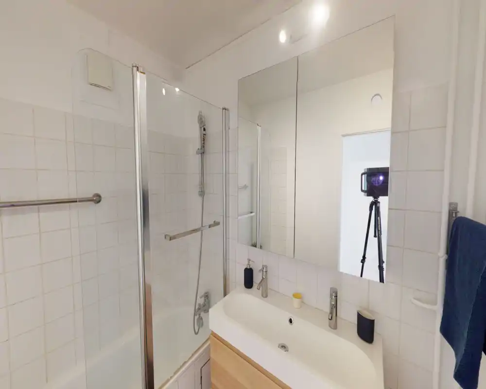 Bright, modern bathroom with a bathtub/shower combination, glass shower screen, double sink countertop and large mirror.