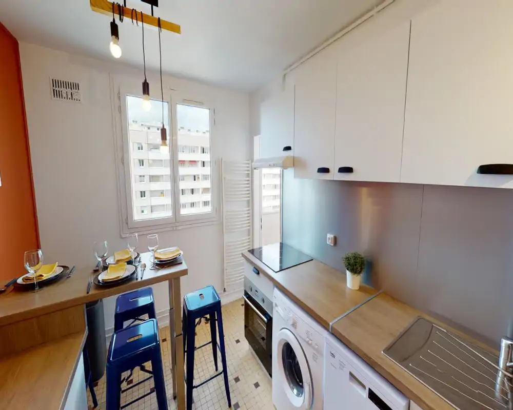 Bright, modern kitchen with wood countertops, a built-in oven and induction hob, breakfast bar set for four and a washing machine under the counter — a compact, well-arranged space.
