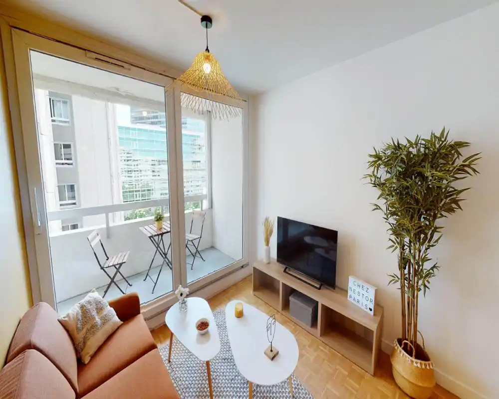 Salon moderne et lumineux avec canapé confortable, tables basses, meuble TV et grandes baies vitrées donnant sur un petit balcon — ambiance chaleureuse et soignée, parfait pour une annonce.