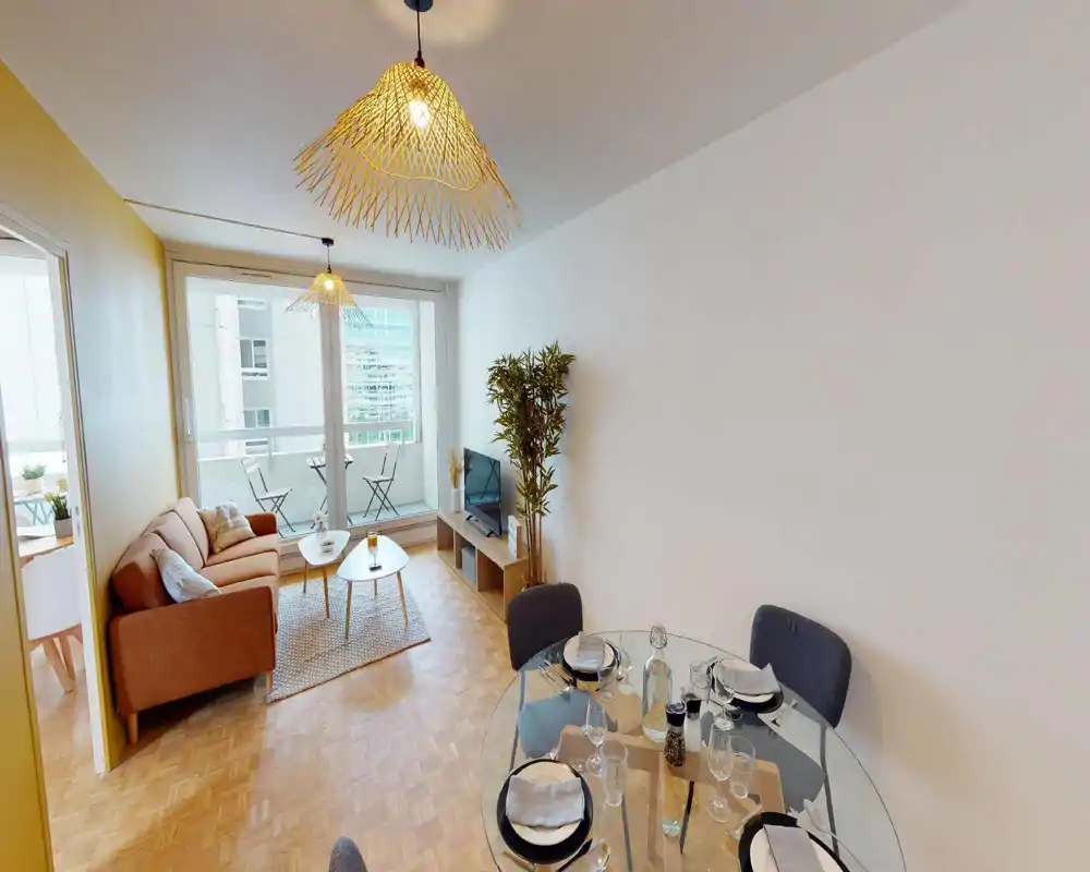 Salon moderne et lumineux avec canapé confortable, tables basses et accès direct à un petit balcon. De grandes baies vitrées apportent une belle lumière naturelle et la décoration comprend textiles chaleureux et plantes.