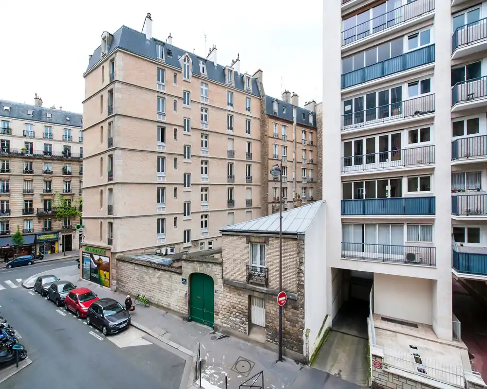 Exterior street view showing multi-story apartment buildings and a small plaza/road; image is heavily artifacted but clearly an outdoor urban scene.