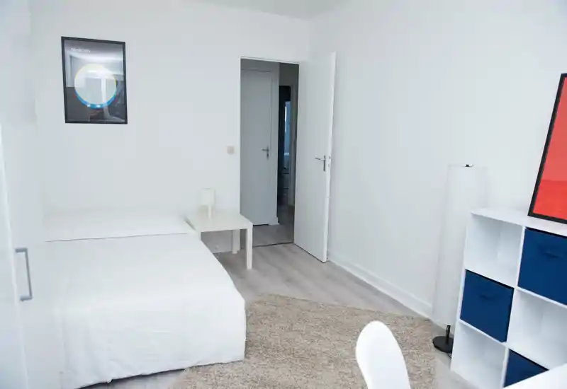 Dormitorio luminoso y minimalista con cama doble blanca, mesita y alfombra suave; decoración nórdica limpia y luz natural que lo hace acogedor.