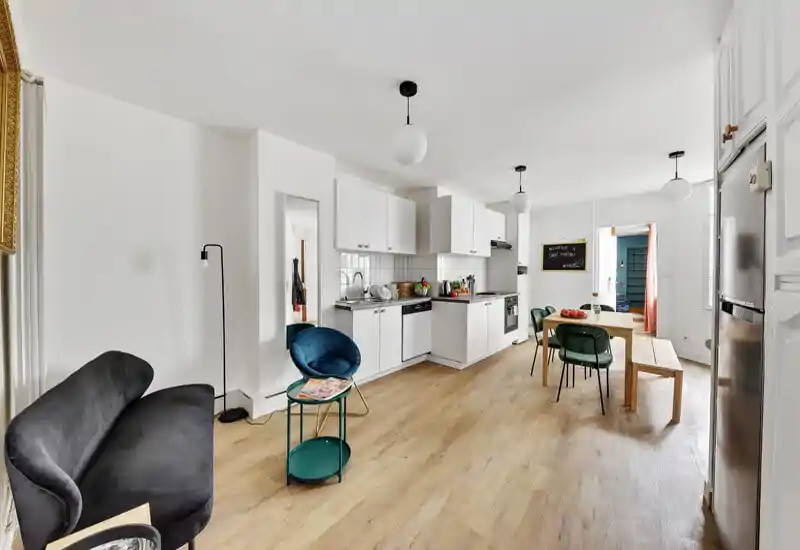 Espace de vie lumineux et moderne en open‑space avec cuisine blanche compacte, table à manger et assises confortables—parfait pour un appartement citadin chaleureux.