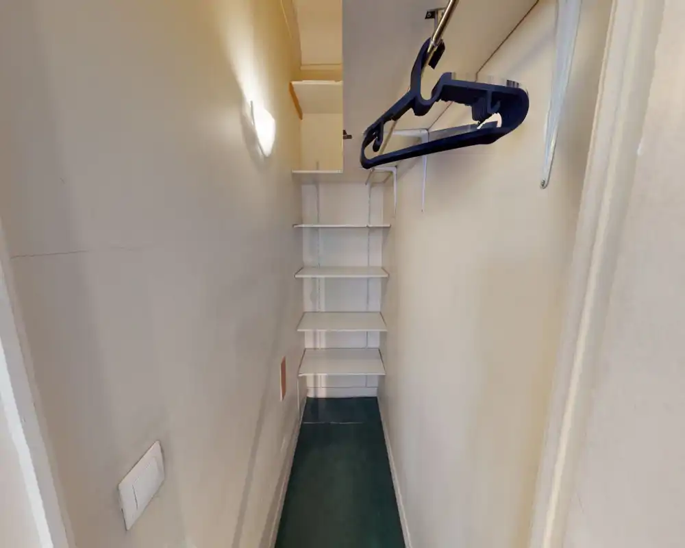 Petit placard d'entrée avec étagères intégrées et tringle pour vêtements. Espace de rangement compact, pratique pour manteaux et chaussures.