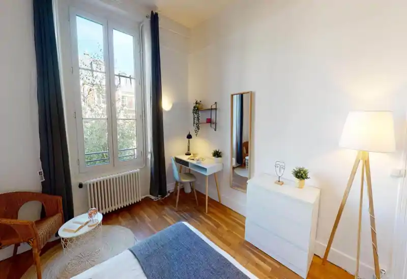 Bright attic bedroom with a sloped ceiling and a visible double bed; the image is strongly distorted by digital artifacts but the room appears cozy and well lit.