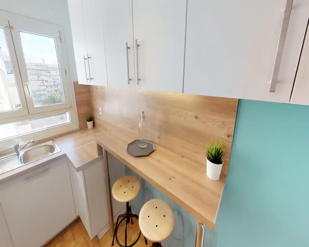 Compact modern kitchen with a wooden breakfast bar, two stools, white cabinets and a sink by a bright window — ideal for a small apartment.