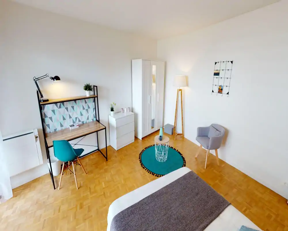 Camera da letto luminosa e di design con letto in primo piano, scrivania con motivo geometrico, armadio e una comoda poltroncina — ideale per un singolo.