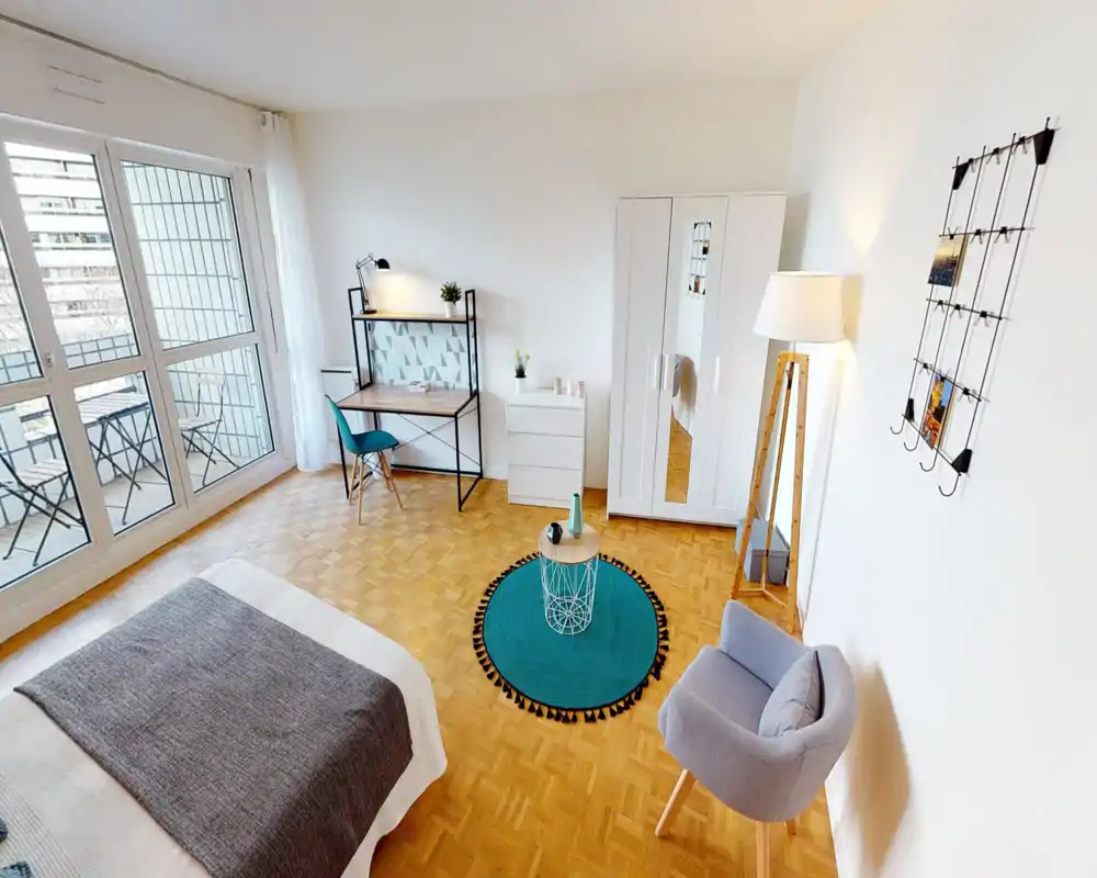 Camera da letto moderna e luminosa con grandi finestre, letto ben rifatto, area studio e accesso al balcone — allestimento curato e illuminazione ideale per annunci.
