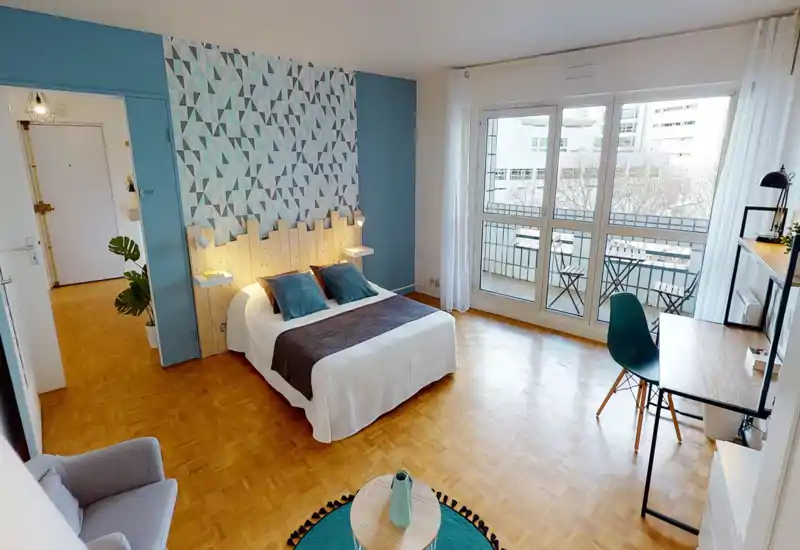 Camera da letto luminosa e di design con letto matrimoniale, testiera decorativa e ampie finestre che si affacciano su un balcone. Pavimenti in legno, scrivania e tessili accoglienti creano un ambiente invitante.
