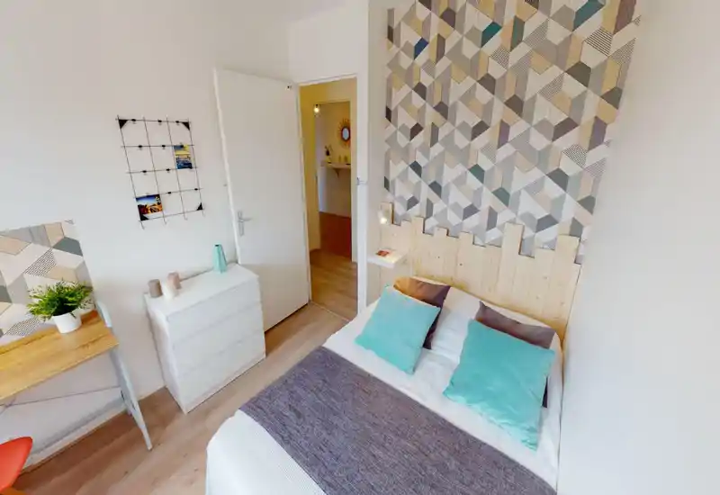 Camera da letto luminosa e ben arredata con letto matrimoniale, parete decorativa a motivi e cuscini coordinati — perfetta per un soggiorno confortevole.