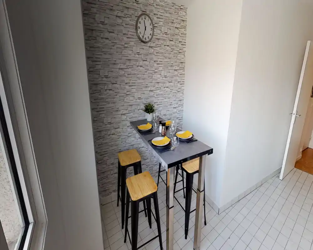 Angolo pranzo moderno e compatto con tavolo alto per quattro persone, sgabelli in legno e parete decorativa — luminoso e adatto a pasti informali.