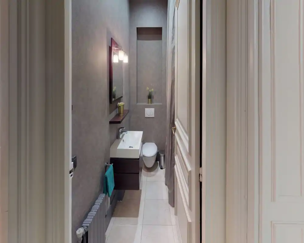 Compact, modern bathroom with wall-mounted sink and toilet, neutral grey walls and soft lighting for a calm atmosphere.