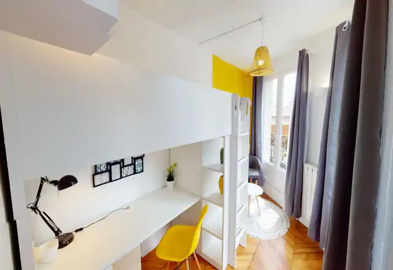 Chambre lumineuse et stylée avec lit mezzanine et bureau intégré, touches jaunes, grandes fenêtres et coin détente — idéale pour un étudiant ou une personne seule.