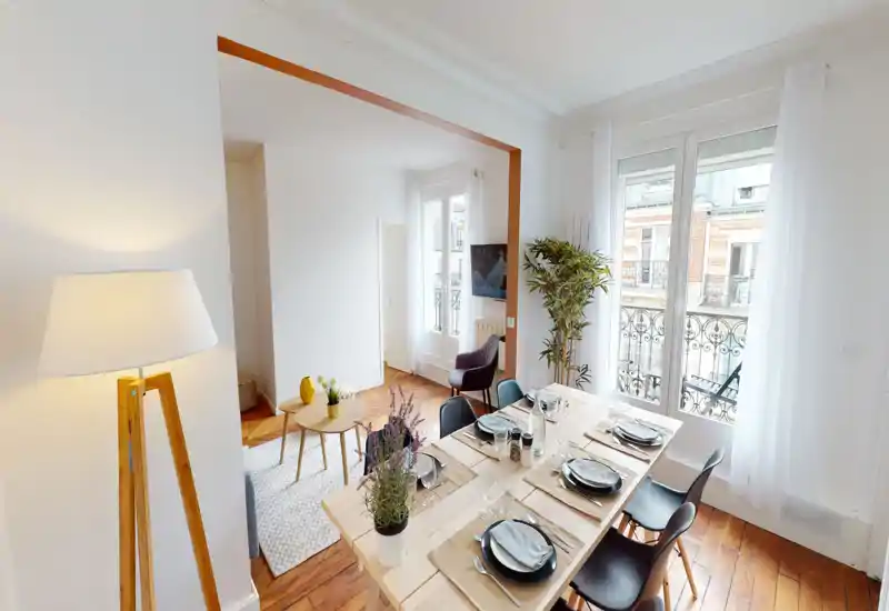 Espace repas lumineux et aménagé, table dressée pour six, parquet et grandes fenêtres donnant sur un balcon — idéal pour des repas conviviaux et pour mettre en valeur la clarté de l'appartement.