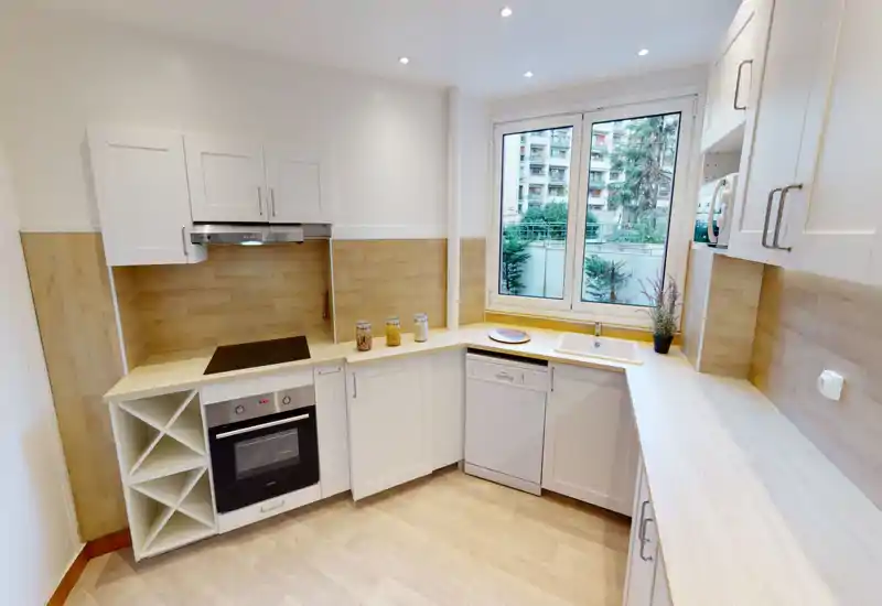 Bright, modern kitchen with white cabinetry, wooden countertops and backsplash, built-in oven and dishwasher, and a large window providing natural light.