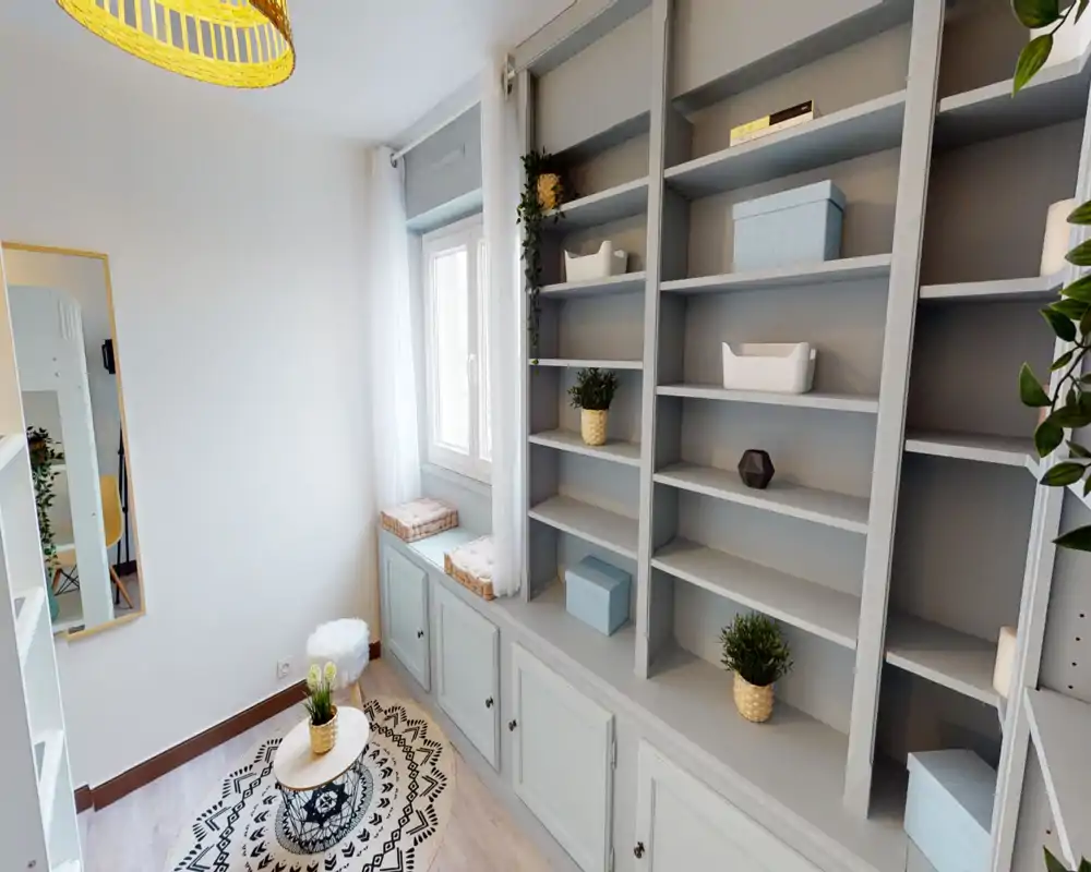 Area giorno luminosa e ben arredata con scaffalature incassate, seduta vicino alla finestra e dettagli decorativi che creano un angolo accogliente per la lettura.