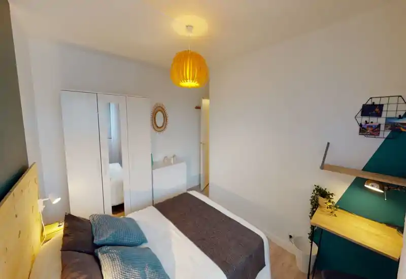 Camera da letto luminosa e ben arredata con comodo letto matrimoniale, lampade da comodino e una piccola postazione di lavoro — perfetta per soggiorni confortevoli o smart working.