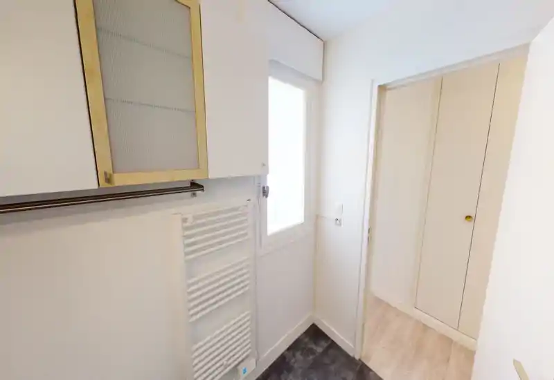 Small bright entrance/hallway with built-in storage doors, a window and a heated towel radiator — neutral, clean design ideal for an apartment entry.