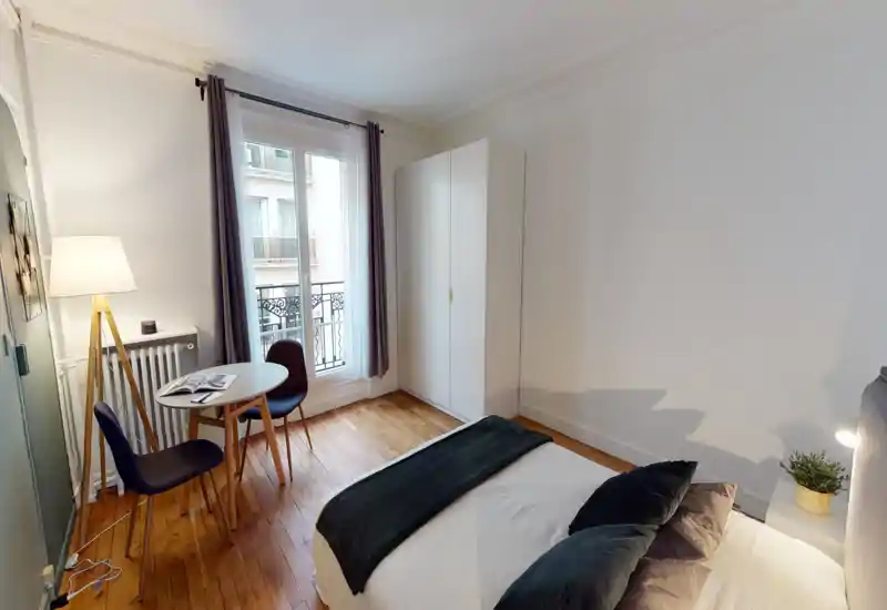 Bright, cosy bedroom with a neatly made bed, soft pillows and a small dining table by the window. Natural light and tasteful decor create a welcoming atmosphere ideal for rental photos.