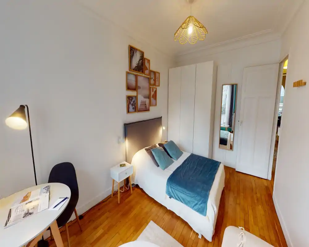 Bright, well-staged bedroom with a double bed, bedside table and wardrobe; warm wood floors and tasteful wall art create a cozy atmosphere.