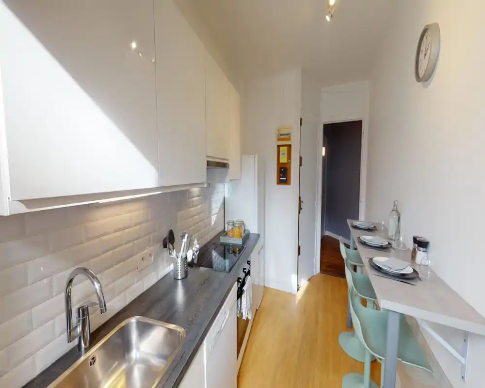 Bright, modern galley kitchen with white cabinets, subway tile backsplash, stainless sink and a breakfast bar with seating for three.