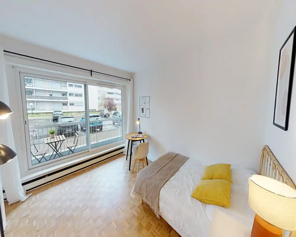 Camera da letto luminosa e moderna con un comodo letto matrimoniale, tessili morbidi e una grande finestra che dà su un piccolo balcone; luce naturale e arredo pulito rendono l'ambiente accogliente.