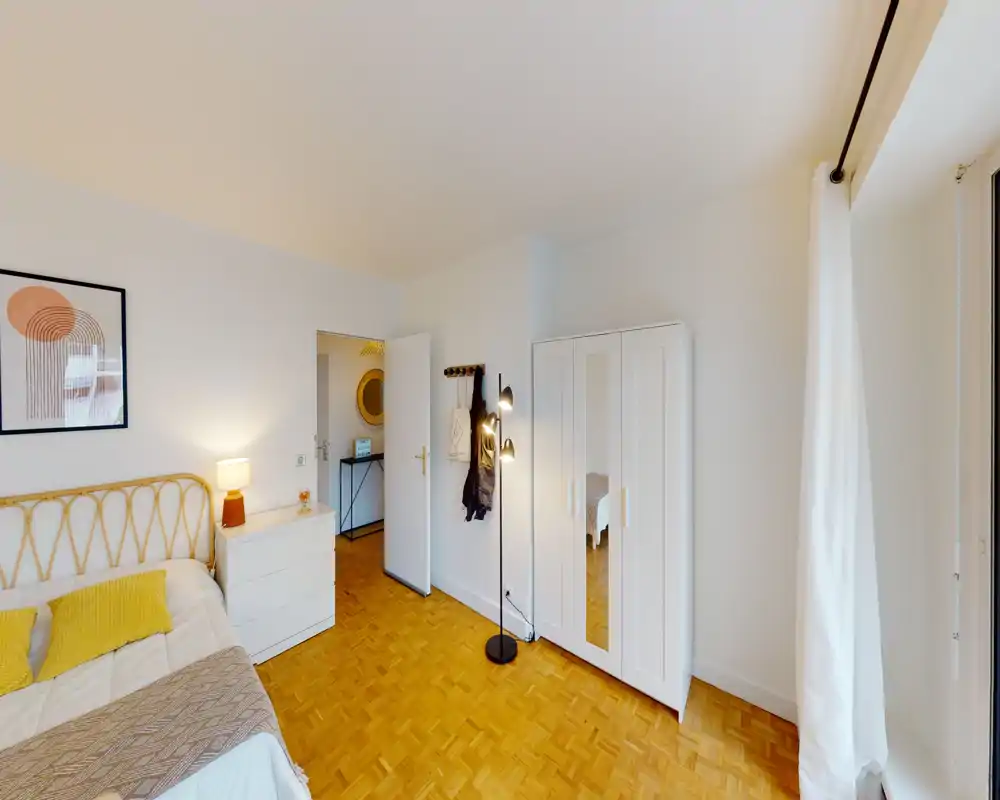 Camera da letto luminosa e ben allestita con letto matrimoniale, lampada da comodino, armadio con anta a specchio e pavimento in parquet — perfetta per un annuncio accogliente.