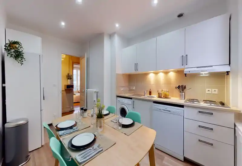 Bright, modern kitchenette with integrated appliances and a set dining table for four — ideal for compact city living.