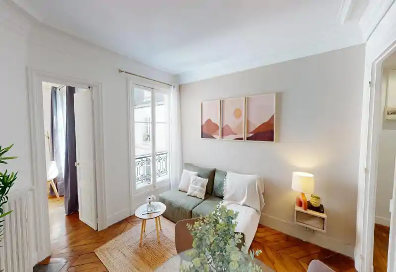 Zona giorno luminosa e di stile con un divano verde confortevole, cuscini decorativi, un piccolo tavolino e una grande finestra che fornisce luce naturale.