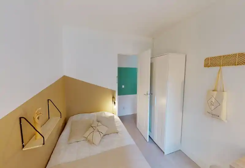 Camera da letto singola luminosa e ben allestita con letto confortevole, parete d'accento ocra e armadio bianco. La stanza è accogliente e ben illuminata, perfetta per annunci di affitto.