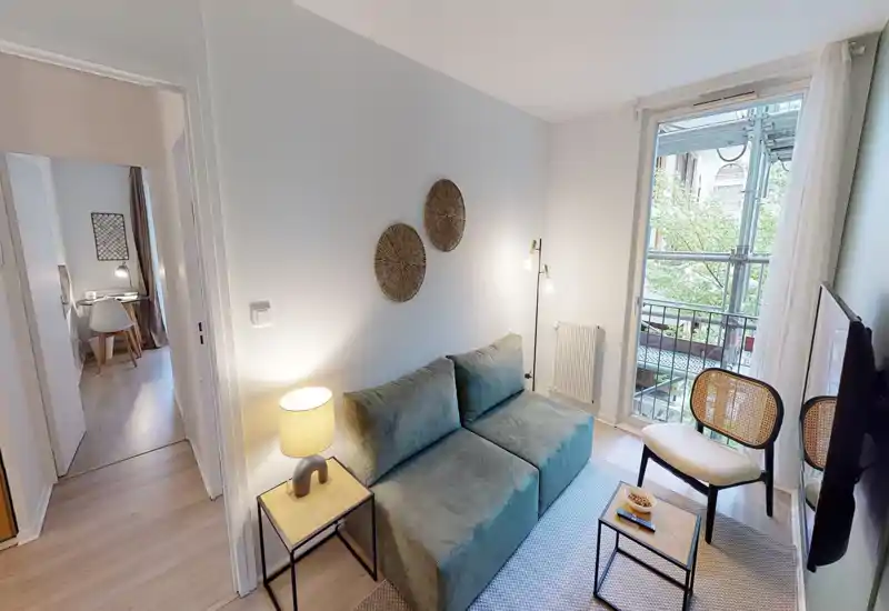 Compact, stylish living area with a comfortable two-seater sofa, accent lighting and a balcony that brings natural light — ideal for a cozy stay.
