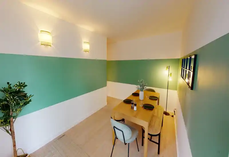 Bright, styled dining area with a wooden table set for four, warm wall and floor lighting, and decorative plants for a cosy, modern feel.