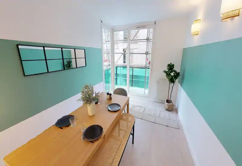 Bright, stylish dining area with a wooden table set for four, decorative vase and natural light from large windows — ideal for meals and socialising.